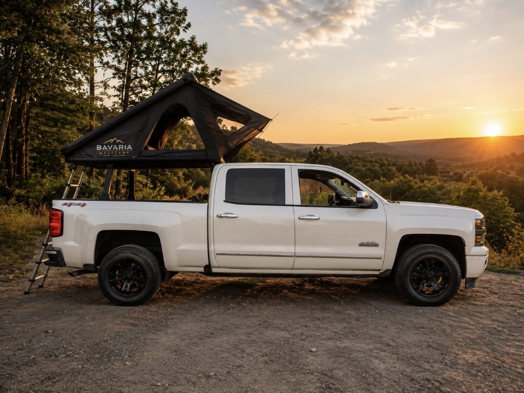 Ein weißer Chevrolet Silverado mit geöffnetem Dachzelt auf einer Anhöhe im Abendlicht.