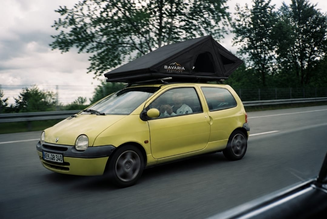 Ein gelber Renault Twingo fährt mit aufgesetztem Dachzelt über die Autobahn.